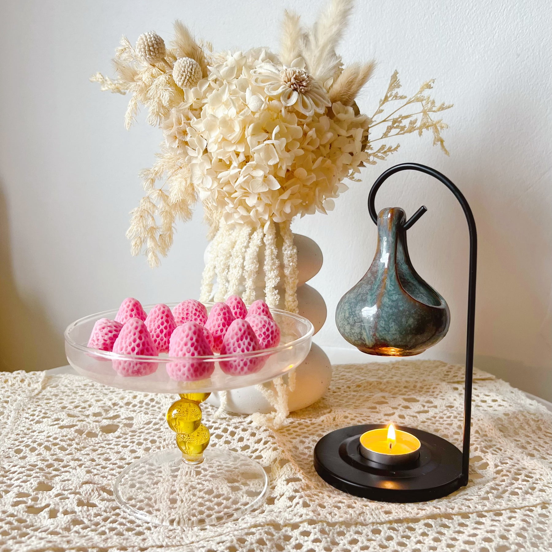 Pack of 12 vibrant red strawberry-shaped soy wax melts by LMJ Candles displayed on ceramic wax warmer and glazed tray, highlighting their unique fruit design and bright colour.