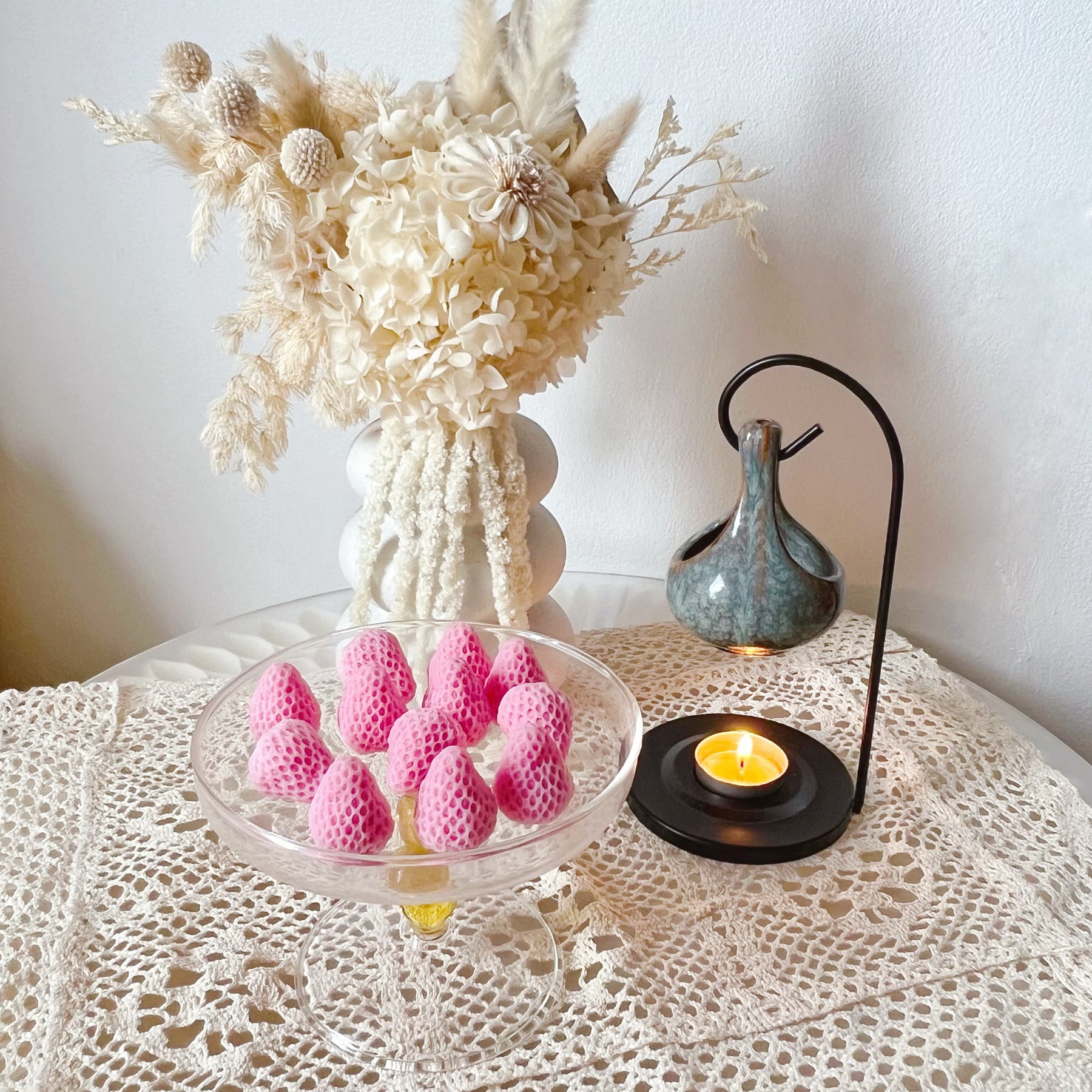 Pack of 12 vibrant red strawberry-shaped soy wax melts by LMJ Candles displayed on ceramic wax warmer and glazed tray, highlighting their unique fruit design and bright colour.