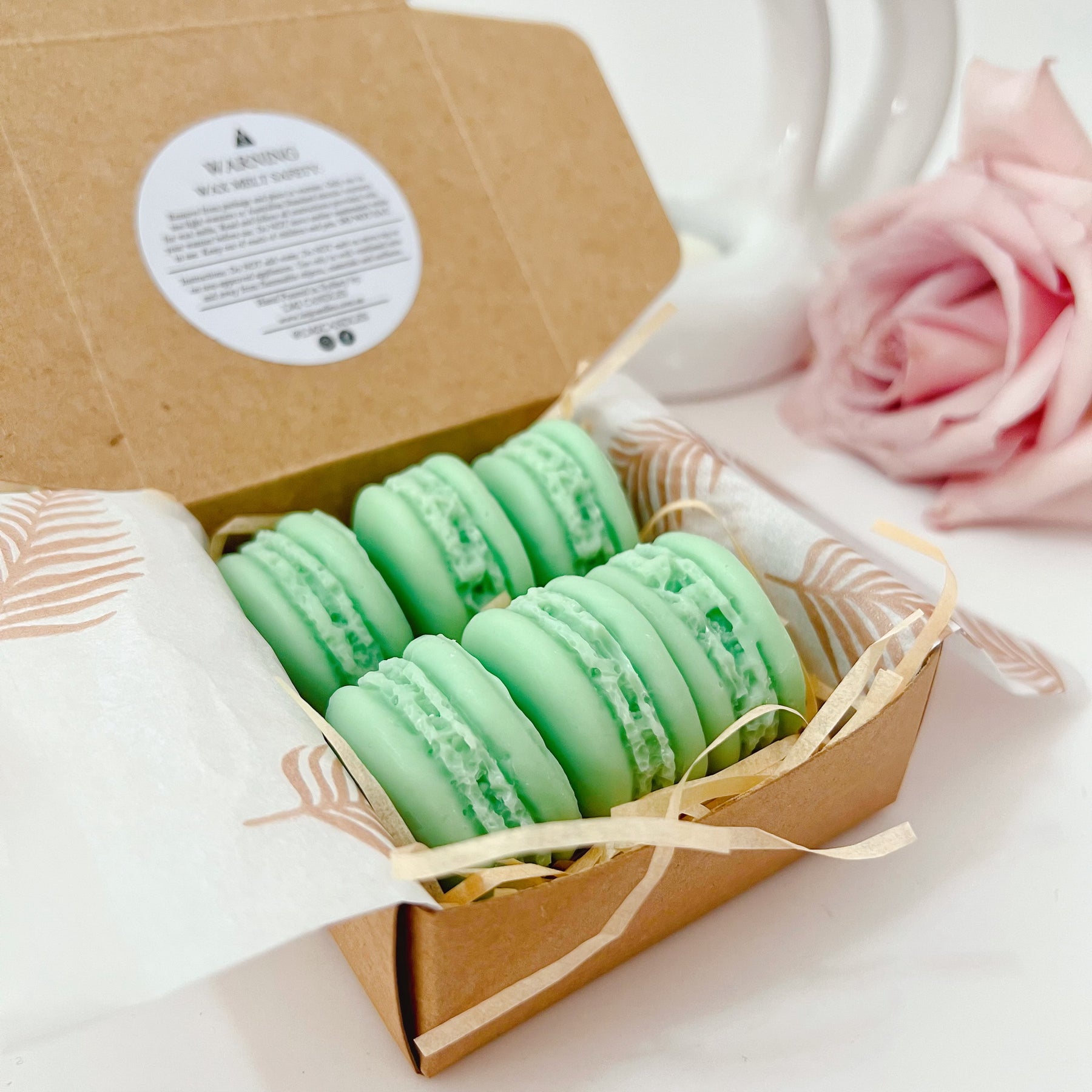 Six colorful macaron-shaped soy wax melts from LMJ Candles artistically arranged on ceramic warmer and cardboard box, showcasing eco-friendly and vegan features.