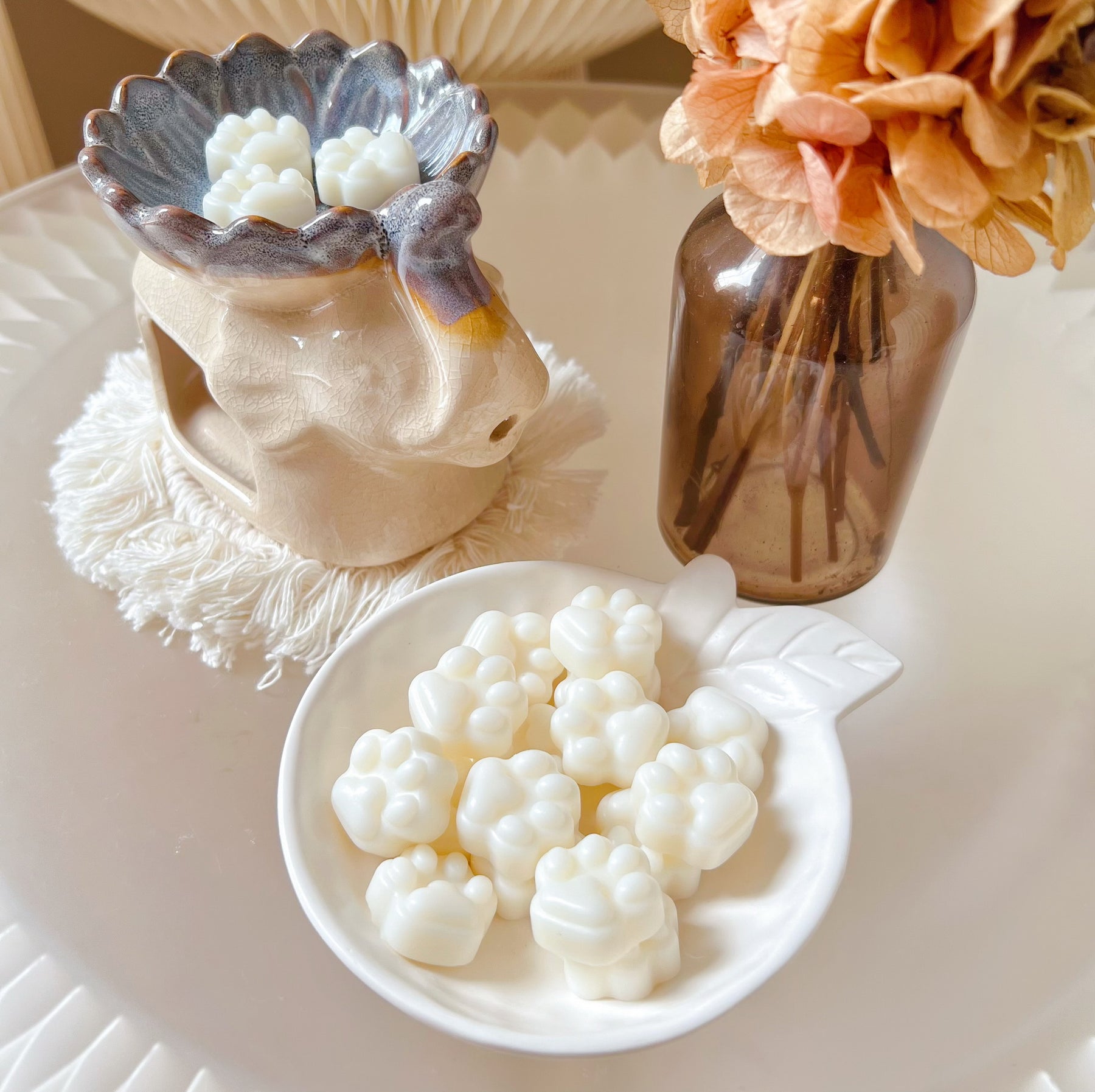 Pack of 20 cute paw-shaped soy wax melts from LMJ Candles displayed on a decorative tray and elephant shaped wax warmer, highlighting the eco-friendly and vegan qualities.