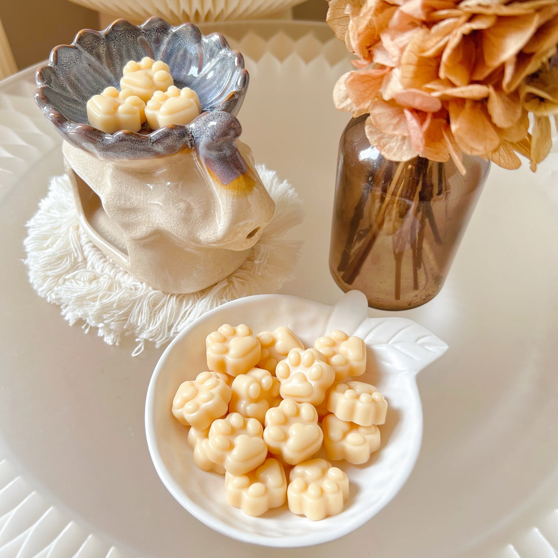 Pack of 20 cute paw-shaped soy wax melts from LMJ Candles displayed on a decorative tray and elephant shaped wax warmer, highlighting the eco-friendly and vegan qualities.