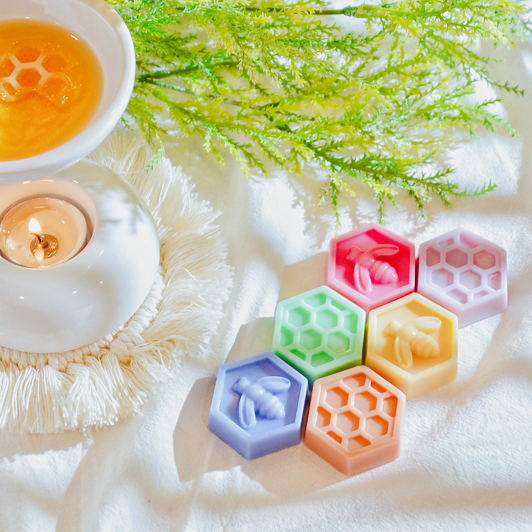 Six bee honeycomb-shaped soy wax melts from LMJ Candles, beautifully arranged on a ceramic wax warmer, showcasing their unique honeycomb design and honey scent.