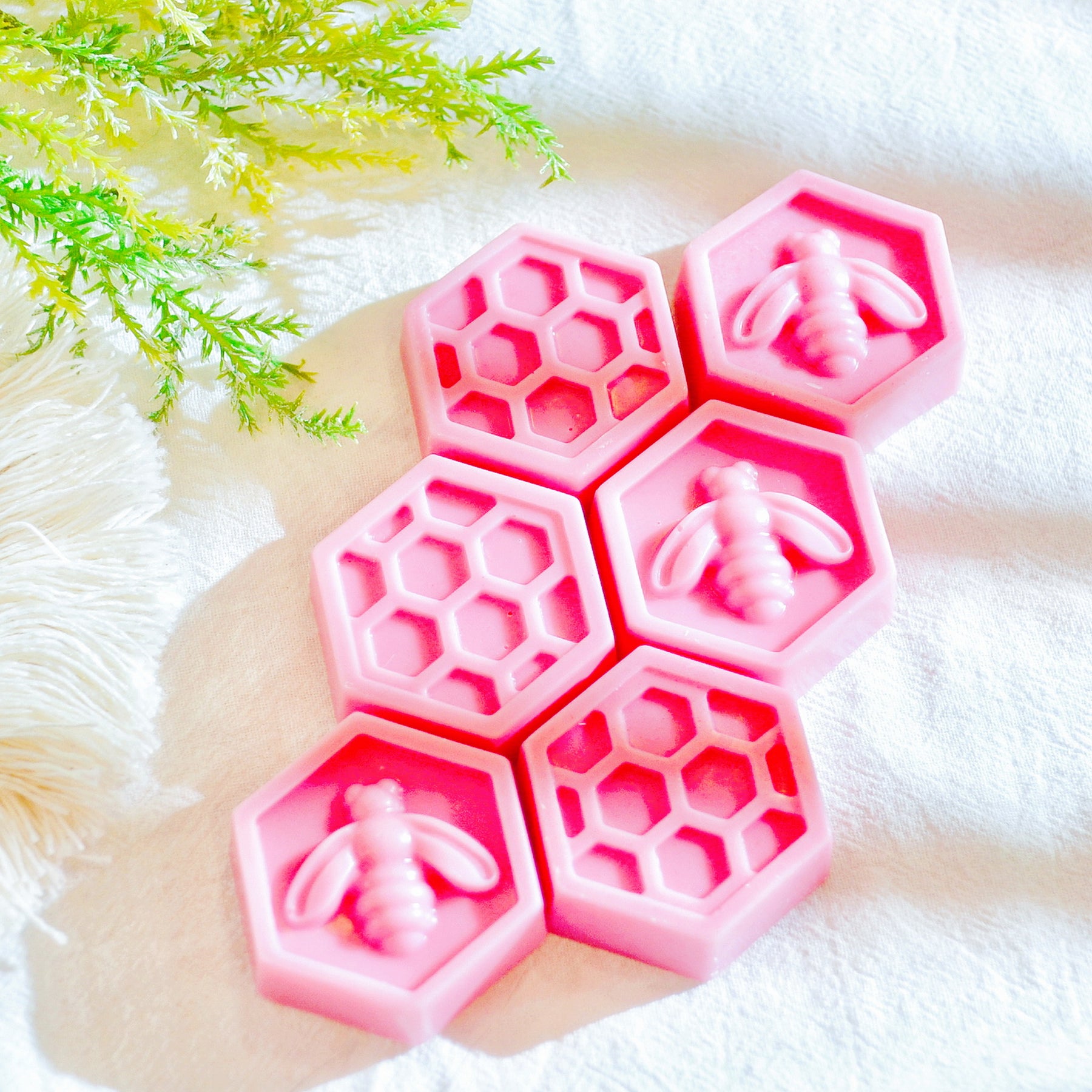 Six bee honeycomb-shaped soy wax melts from LMJ Candles, beautifully arranged on a ceramic wax warmer, showcasing their unique honeycomb design and honey scent.