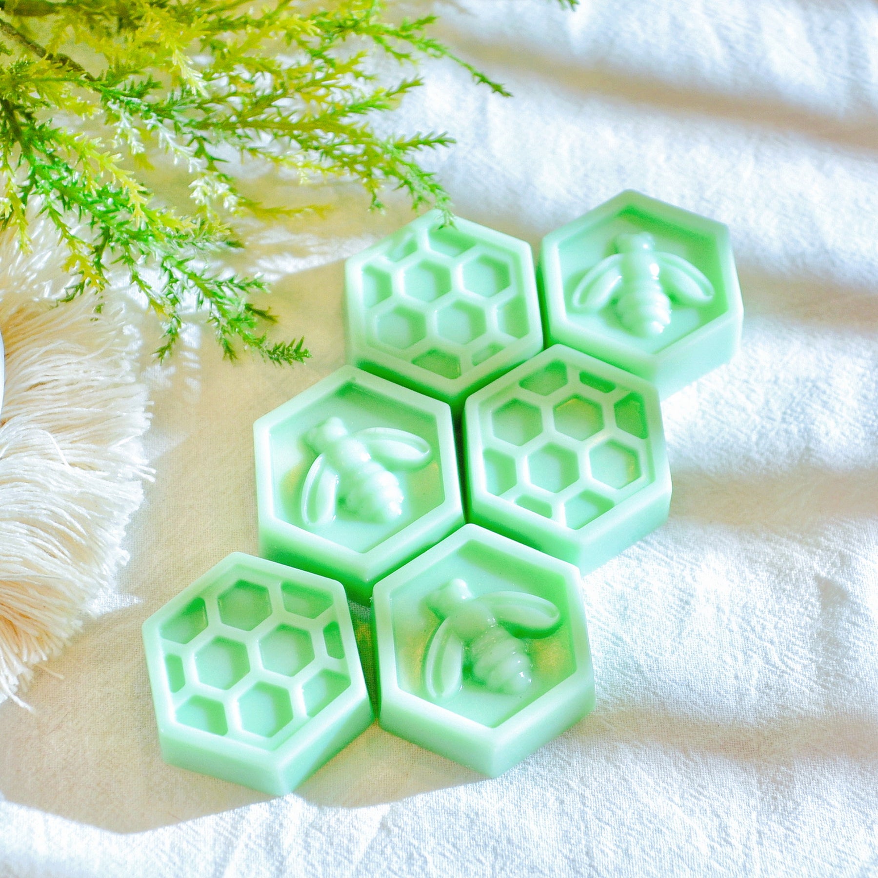 Six bee honeycomb-shaped soy wax melts from LMJ Candles, beautifully arranged on a ceramic wax warmer, showcasing their unique honeycomb design and honey scent.