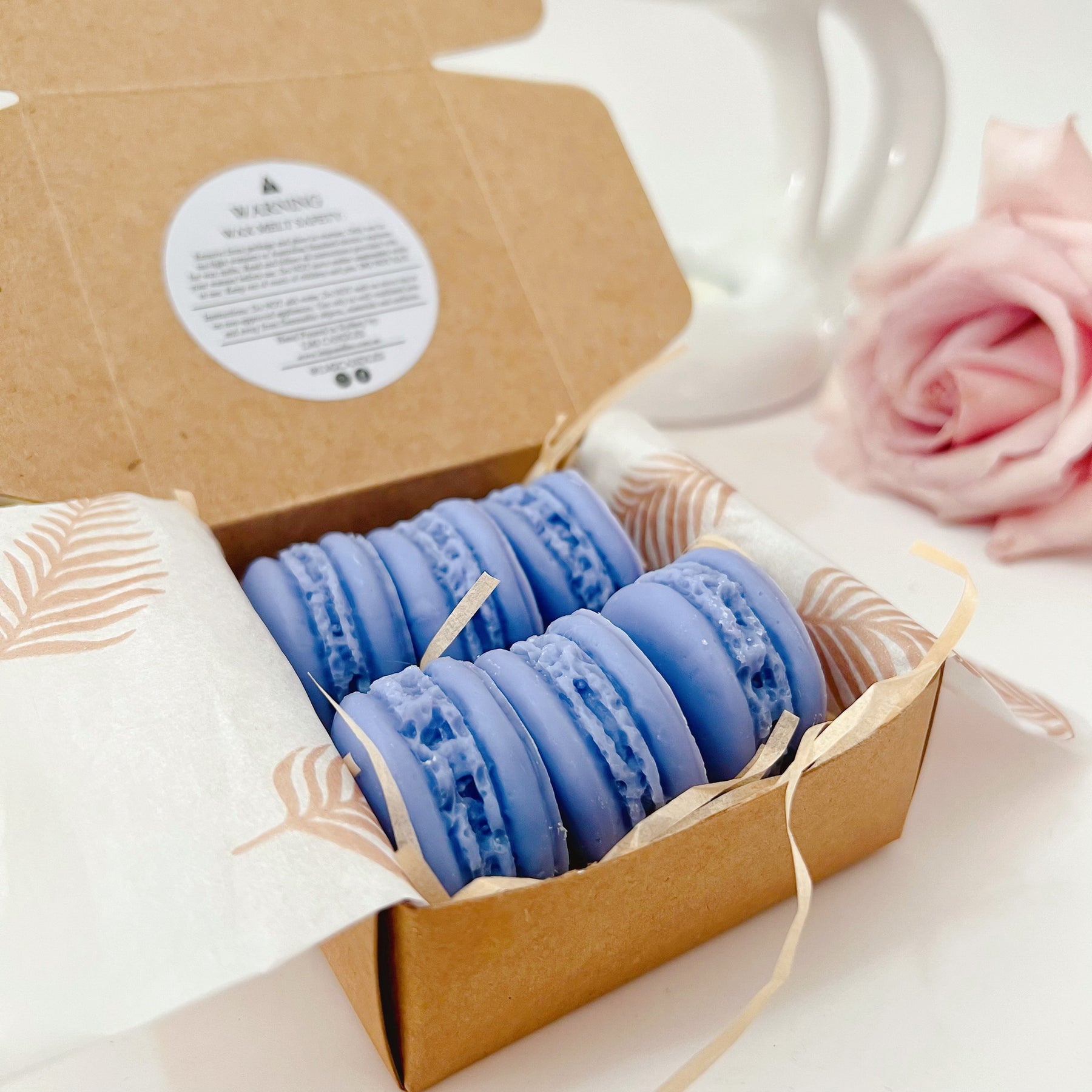 Six colorful macaron-shaped soy wax melts from LMJ Candles artistically arranged on ceramic warmer and cardboard box, showcasing eco-friendly and vegan features.
