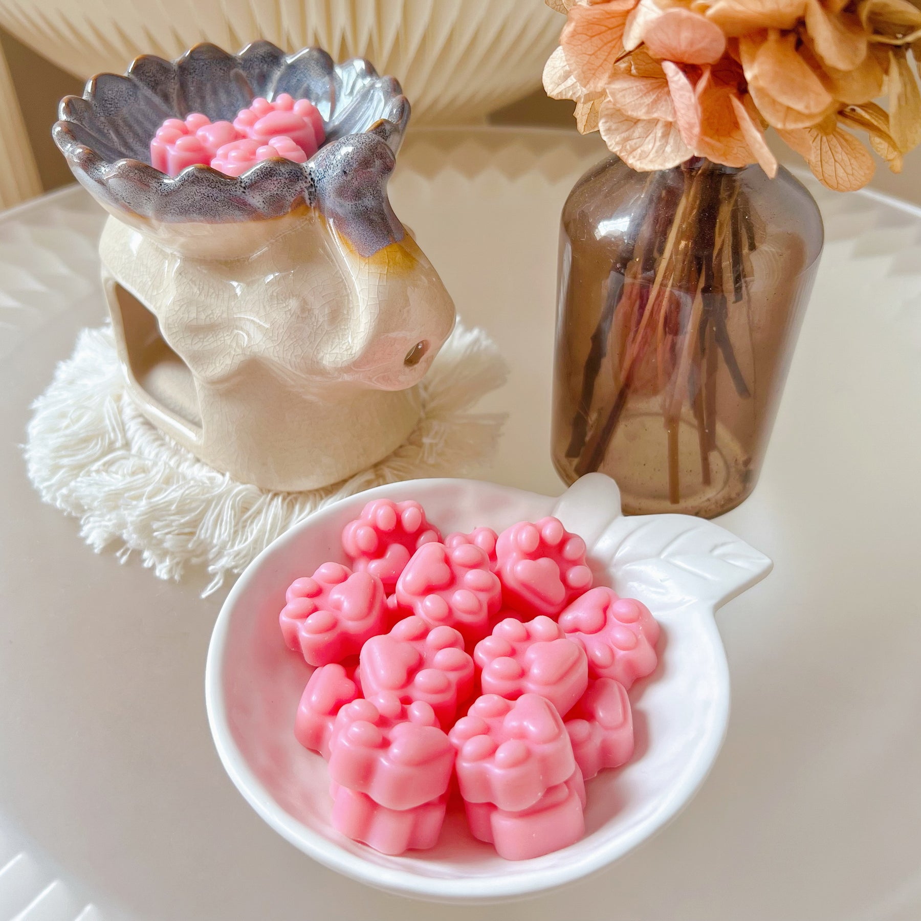 Pack of 20 cute paw-shaped soy wax melts from LMJ Candles displayed on a decorative tray and elephant shaped wax warmer, highlighting the eco-friendly and vegan qualities.