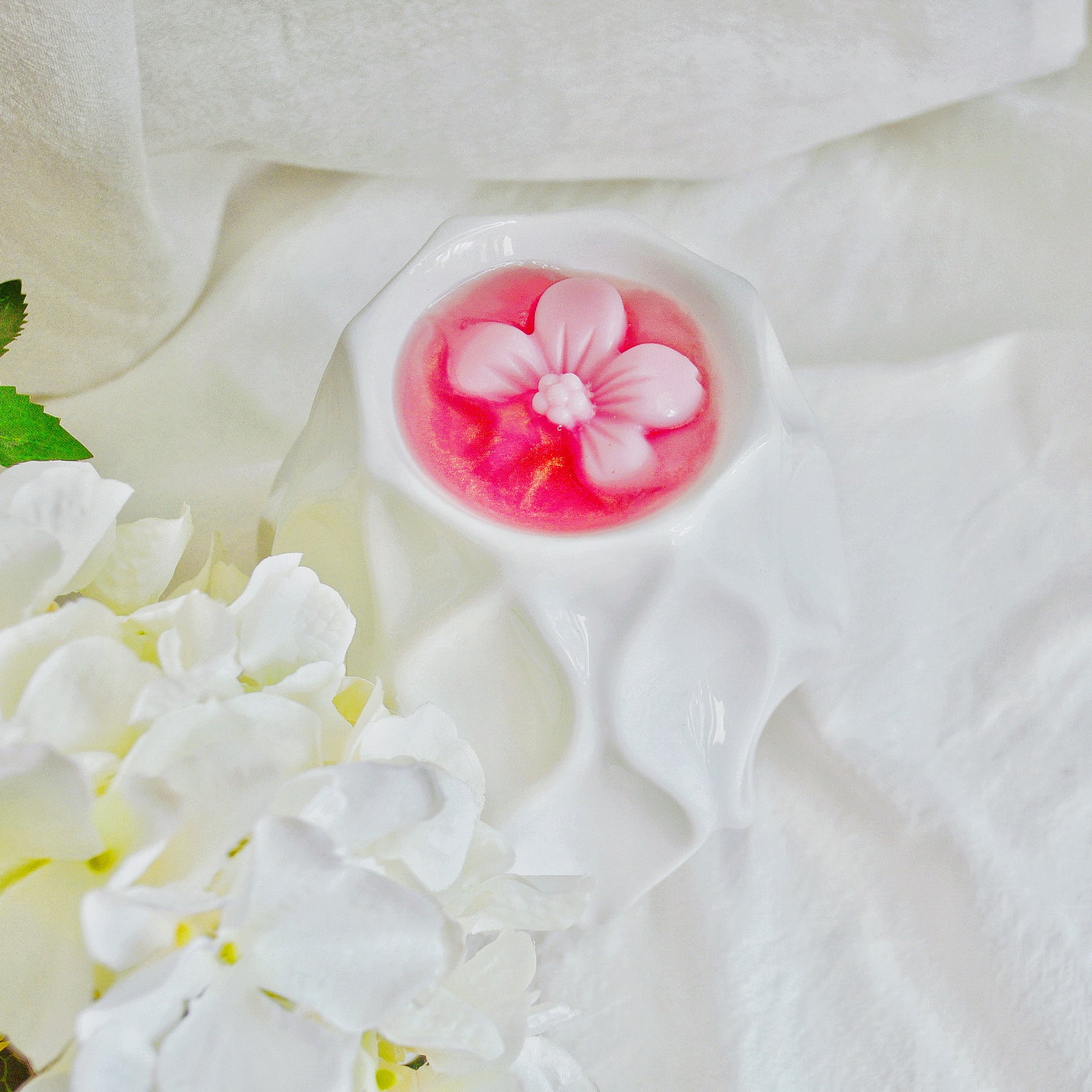 Six cherry blossom soy wax melts by LMJ Candles, beautifully presented on a ceramic warmer beside their eco-friendly cardboard box, highlighting their floral fragrance and vegan qualities.