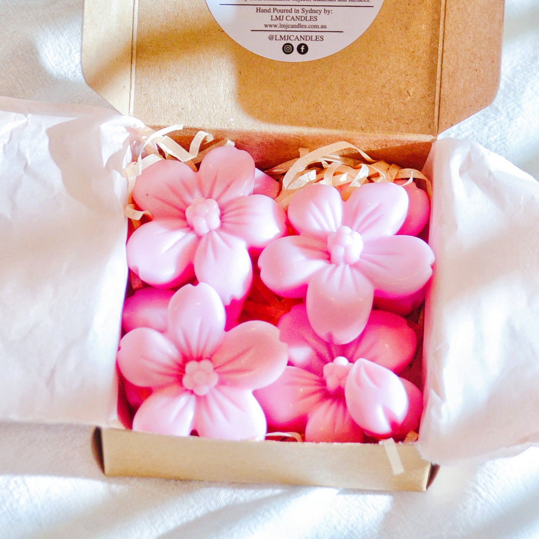 Six cherry blossom soy wax melts by LMJ Candles, beautifully presented on a ceramic warmer beside their eco-friendly cardboard box, highlighting their floral fragrance and vegan qualities.