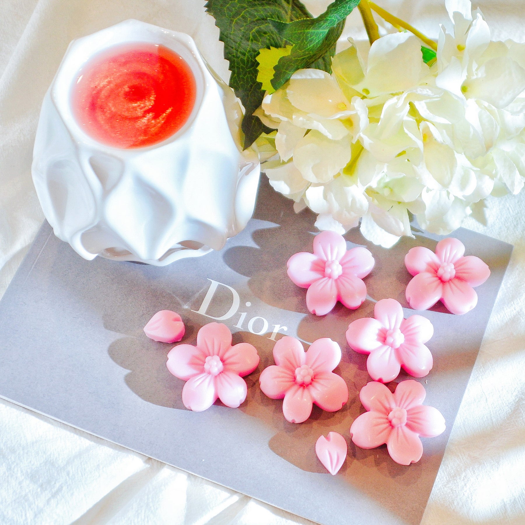 Six cherry blossom soy wax melts by LMJ Candles, beautifully presented on a ceramic warmer beside their eco-friendly cardboard box, highlighting their floral fragrance and vegan qualities.