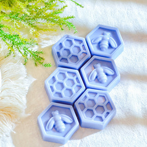 Six bee honeycomb-shaped soy wax melts from LMJ Candles, beautifully arranged on a ceramic wax warmer, showcasing their unique honeycomb design and honey scent.