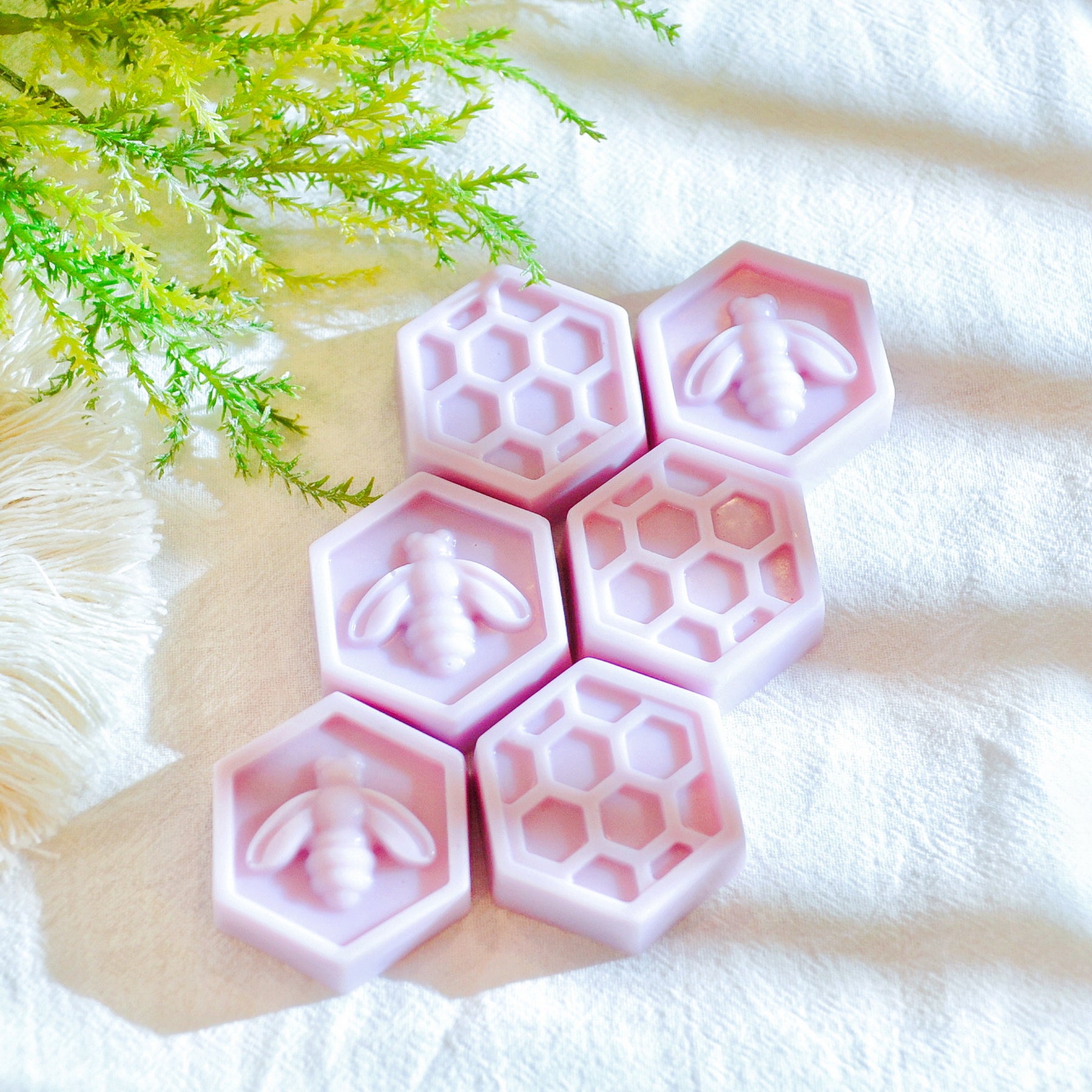 Six bee honeycomb-shaped soy wax melts from LMJ Candles, beautifully arranged on a ceramic wax warmer, showcasing their unique honeycomb design and honey scent.